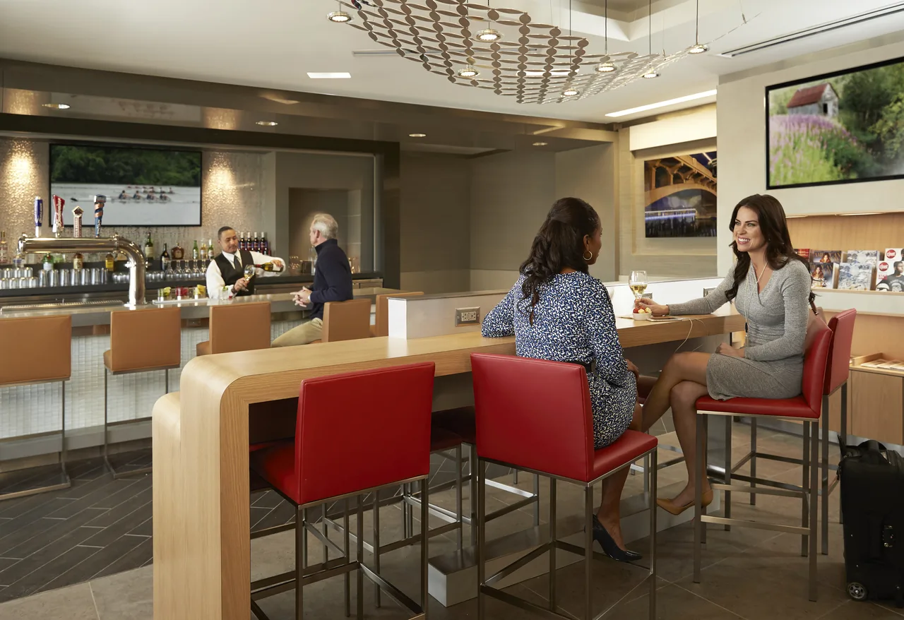 Admirals Club bar with travellers, representing the lounge-day-pass benefits sometimes affected by transferable-points devaluations.