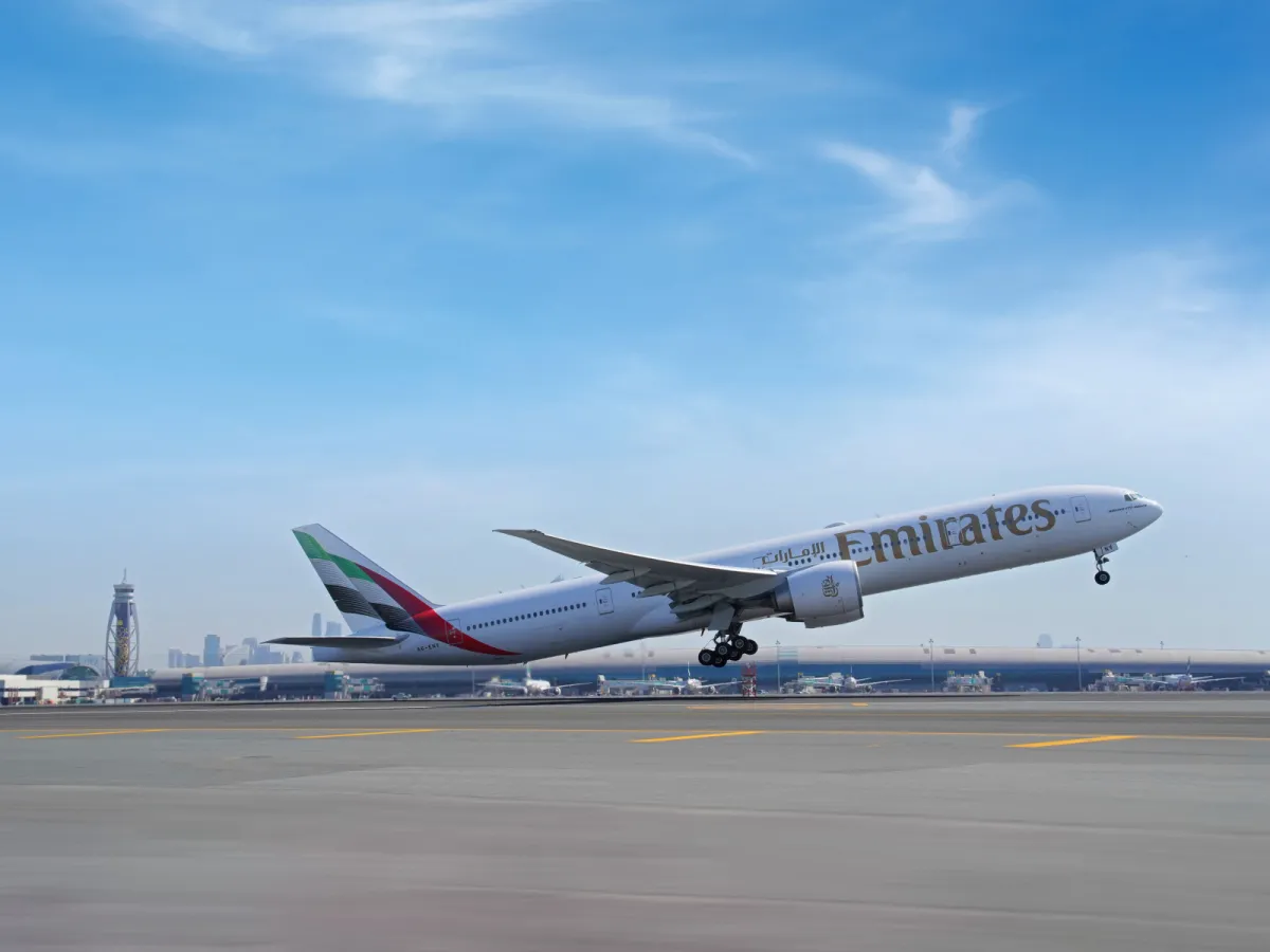 Emirates Boeing 777-300ER taking off from Dubai International Airport against a clear blue sky