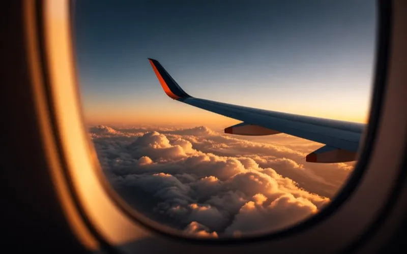 Cabin-window view of an aircraft wing at golden hour